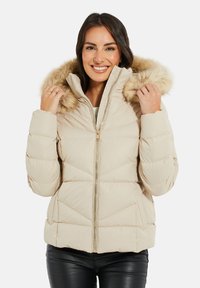 Beige Steppjacke mit gefütterter Kapuze aus Fell, gestepptem Design, Frontreißverschluss und elastischen Bündchen. Texturiert mit leicht glänzendem Finish.