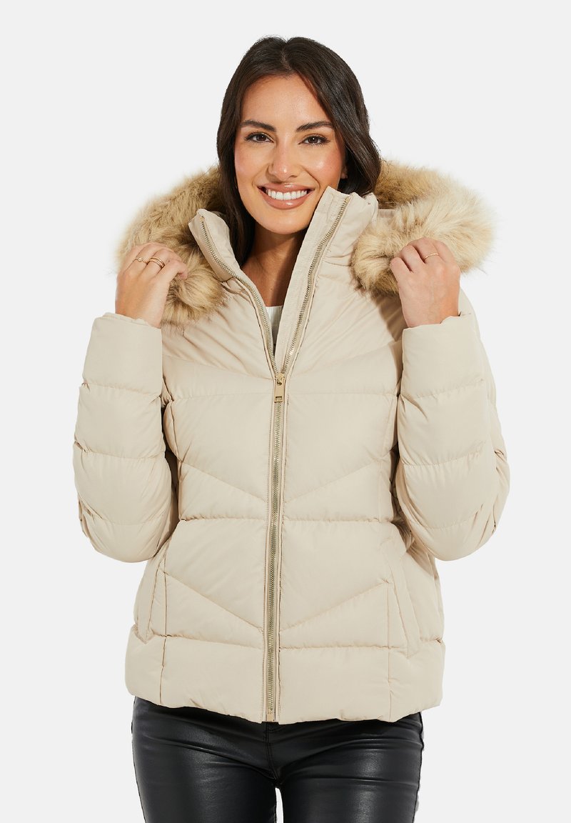 Beige Steppjacke mit gefütterter Kapuze aus Fell, gestepptem Design, Frontreißverschluss und elastischen Bündchen. Texturiert mit leicht glänzendem Finish.