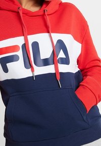 Röd, vit och marinblå färgblockerad hoodie i bomullsblandat tyg. Har logotyp, justerbara dragsko och framficka.