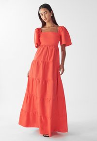 Maksimālais kleita spilgti oranžā krāsā ar kvadrātveida izgriezumu, puff piedurknēm, slāņotu dizainu un gludu, vieglu audumu.