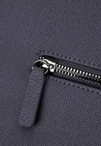 Gray fabric bag featuring a textured surface, metal zipper with a pull tab, and detailed stitching along the zipper line.