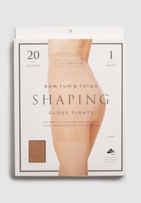 Nude 20 denier tvarovacie lesklé pančuchy v obale, označené "Bum, Tum & Thigh." Na strane je zasunutý vzorovaný kus látky. Obsahuje 1 pár.