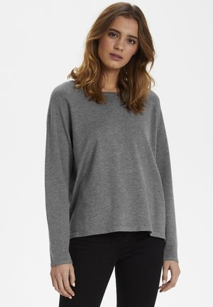 Suéter gris de manga larga con un corte relajado, cuello redondeado y textura suave, combinado con pantalones negros. Sin patrones ni detalles visibles.