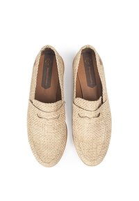 Zapatos de color beis tejidos con una superficie texturizada, punta redondeada y suela de madera plana. Costura decorativa cerca de la apertura. Diseño simple.