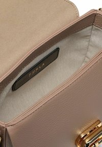 Piccola borsa a mano beige in pelle con rivestimento interno testurizzato e chiusura in metallo color oro, con etichetta nera con il nome del marchio Furla all'interno.