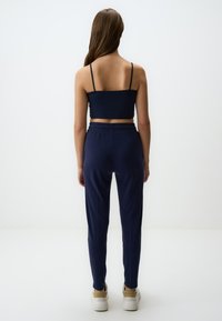 Navyblauwe cropped tanktop met spaghettibandjes, gecombineerd met bijpassende tapered broek met een elastische tailleband en enkelmanchetten.