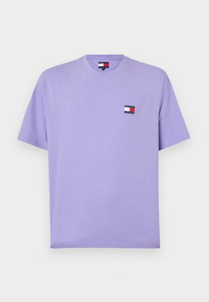 Violetinis medvilninis marškinėliai trumpomis rankovėmis, apvaliu kaklu ir mažuoju daugiaspalviu logotipu ant kairiojo krūtinės. Lygus paviršius.
