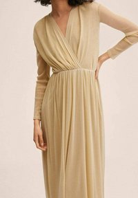 Robe longue de couleur champagne en tissu léger ; présente un design enveloppant, des manches longues et une taille froncée pour un drapé fluide.