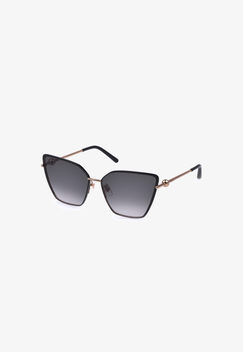 Lunettes de soleil œil-de-chat noires et dorées avec verres teintés dégradés foncés et branches métalliques fines, présentées sur fond blanc.