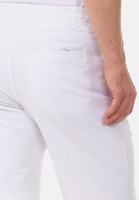 Weisse Baumwollshorts mit einem elastischen Bund und einer Gesäßtasche. Der Stoff wirkt glatt und leicht.