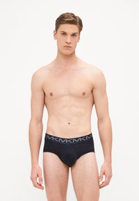 Boxer en coton noir avec une ceinture élastique grise arborant des détails de logo. Le design est ajusté avec une texture lisse et sans motifs visibles.