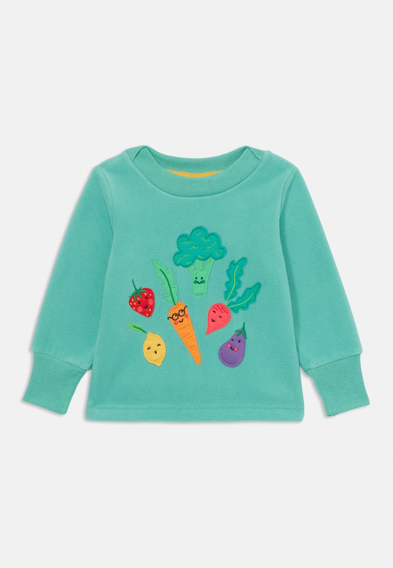 Tirkīza garām piedurknēm svārki ar krāsainiem izšūtiem dārzeņiem un augļiem, tostarp brokoļiem, burkāniem, zemeņu un citronu.