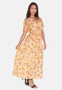 Maxi abito floreale in tessuto leggero con fiori arancioni, gialli e rosa. Scollo a V, maniche corte e vita elastica. Dettaglio con spacco all'orlo.