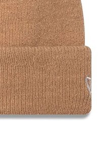 Bonnet en tricot couleur brun clair, avec un revers replié, une texture à côtes fines et un petit logo blanc sur le côté.