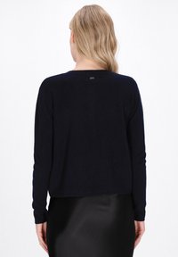 Marinena blue sweater van zachte stof met lange mouwen en een ronde hals. Heeft minimale branding op de achterkant en een ontspannen pasvorm.