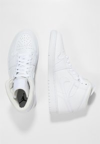 Vita högskor gjorda av läder med perforerad tås, platta snörningar, vadderad krage och strukturerade sulor. Minimalistisk design med logotypdetalj.