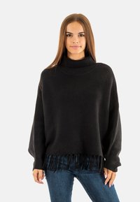 Pull en tricot noir à col roulé avec texture côtelée et ourlet à franges, présentant une coupe ample et de longues manches pour le confort et le style.