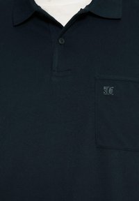 Polo shirt blu navy scuro realizzato in tessuto liscio, con colletto classico, taschino frontale e un piccolo logo sulla tasca.