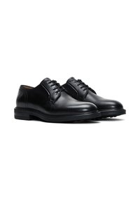 Zwarte leren brogues met een gladde textuur, ronde neus en een vetersluiting met drie oogjes; heeft een lage gestapelde hak en subtiele stiksels.