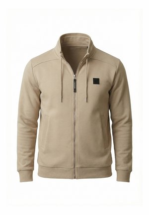 Beige jas met rits en opstaande kraag, voorzakken, trekkoorden, geribbelde manchetten en een klein zwart vierkant logo op de linkerborst.