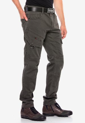 Pantalons cargo en coton vert foncé, dotés de plusieurs poches, de détails de couture et d'une passante de ceinture. Associés à des bottes à lacets marron.