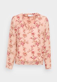 Blusa floreale in tessuto rosa chiaro, con scollatura a V e dettagli volant, maniche lunghe e un motivo floreale sparso in tonalità di rosa e marrone.