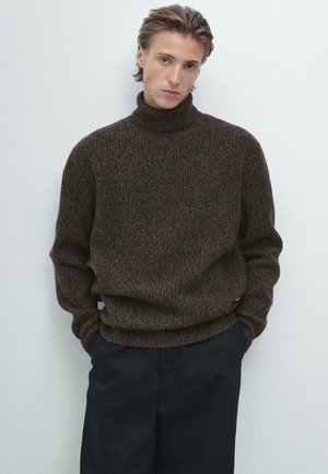 Bruine gebreide coltrui met een textuur en een ontspannen pasvorm. Draagt bij donkere broeken, met ribgebreide manchetten en een zoom.