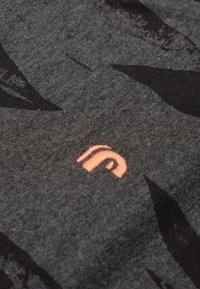 Grijze stof met zwarte bladerenachtige patronen. Bevat een klein, roze geborduurd logo. Zachte textuur, close-up weergave.