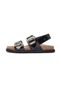 Sandalias negras con dos correas ajustables, adornos de hebilla dorada y una plantilla de corcho sobre una suela de goma negra texturizada.