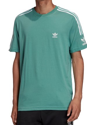 T-shirt en coton turquoise avec col rond, manches courtes et détails à trois rayures blanches sur les épaules. Présente un petit logo Adidas blanc sur la poitrine.