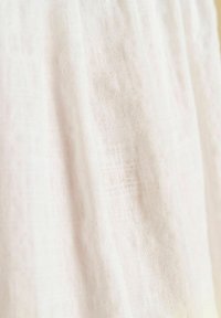 Leichtes Leinengewebe in sanftem Weiß mit einer subtilen Textur, das eine leicht durchscheinende Qualität und einen natürlichen, atmungsaktiven Fall aufweist.