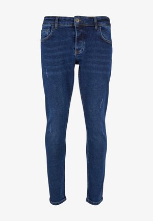 Kitsad teksad tumesinises denimis, millel on klassikaline viie-tasku disain, kerge pleekimine ja peened kulumised jalgadel.