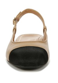 Beige Flachschuh mit einer schwarzen Stoffzehenkappe, verstellbarem Knöchelriemen, glatter synthetischer Oberfläche und runder Zehenform.