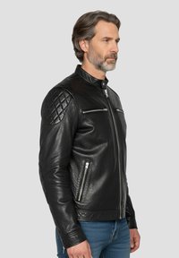 Veste de moto en cuir noir avec fermeture éclair à l'avant, épaules matelassées, poches latérales et coupe ajustée.
