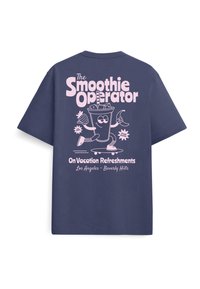 Μπλε σκούρο t-shirt με ροζ γραφικό ενός χαμογελαστού ποτηριού smoothie που κρατά φρούτα, κείμενο «The Smoothie Operator» και «On Vacation Refreshments».