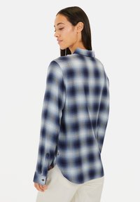 Blauw-wit geruit overhemd met een relaxed fit, lange mouwen en een kraag. Heeft een afgeronde zoom en knoopmanchetten.