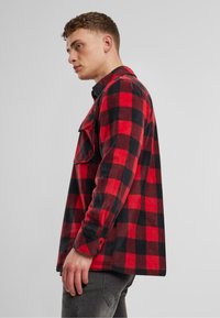 Rot-schwarz kariertes Flanellhemd mit lockerem Schnitt, ausgestattet mit langen Ärmeln und einer Brusttasche, gefertigt aus weichem, strukturiertem Stoff.