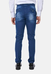 Jeans in denim blu slim-fit con un leggero effetto sbiadito, caratterizzati da due tasche posteriori con chiusura a bottone e una texture liscia.