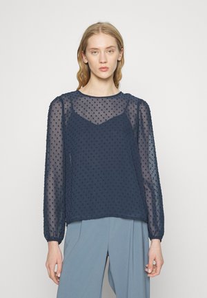 Blusa transparente azul-marinho com mangas longas e bufantes, apresentando bolinhas texturizadas e um decote arredondado. Tecido suave e leve, com um corte relaxado.