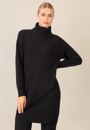 Schwarzer Strickrollkragensweater mit langen Ärmeln, geripptem Saum und lockerer Passform, der eine sanfte Textur und ein minimales Design aufweist.