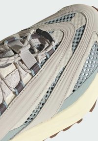 Sivé športové topánky s sieťovými panelmi, štruktúrovanou suede textúrou a tenkými svetlomodrými akcentmi. Majú pevnú podrážku a šnurovací uzáver.