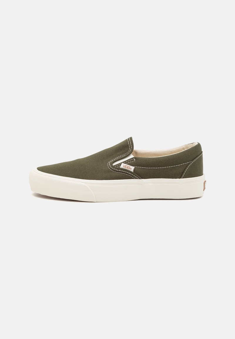 Gröna canvas slip-on skor med vita gummisulor och sömnadsdetaljer. Rund tå och minimalistisk design. Accentuerad logotag på sidan.