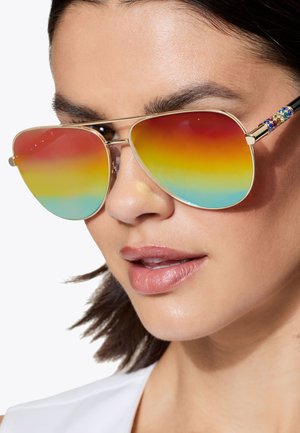 Aviator zonnebrillen met een verlopen gradient van rood naar blauw in de lenzen en gouden accenten. De slapen zijn versierd met kleurrijke edelstenen. Het montuur heeft een slanke metallic afwerking.