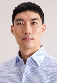 Koszula na guziki w jasnoniebieską i białą kratę, z kołnierzykiem, o klasycznym kroju i gładkiej teksturze. Bez widocznych wzorów czy ozdób.