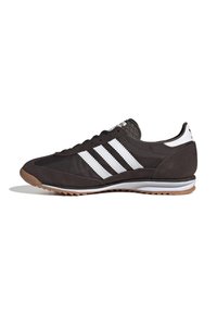 Scarpa sportiva nera realizzata in suede e materiali sintetici, con tre strisce bianche, suola in gomma e dettaglio testurizzato sul tallone.