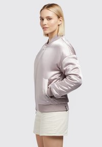 Jachetă bomber din satin roz deschis, cu manșete și tiv ribb. Are buzunare laterale și închidere cu fermoar în față. Textură netedă, croi casual.
