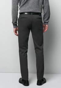 Gray cotton chinos with a straight-leg design, two rear pockets, and a black belt. Textured sweater visible above the waist.