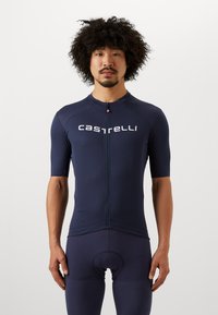 Maillot de cyclisme bleu marine à manches courtes, avec une fermeture éclair à l'avant et le logo "Castelli" imprimé en évidence. Le matériau semble ajusté et lisse.