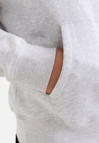 Grauer Sweatshirt mit geripptem Bund und einer Fronttasche. Weiche Textur mit melierten Muster, entworfen für Komfort und lässiges Tragen.