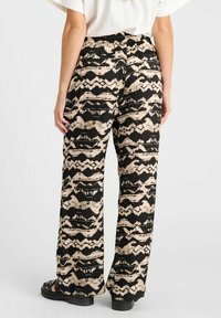 Pantalons à motif noir et beige avec une coupe décontractée, dotés d'une taille extensible et de jambes larges, fabriqués dans un tissu lisse et léger.